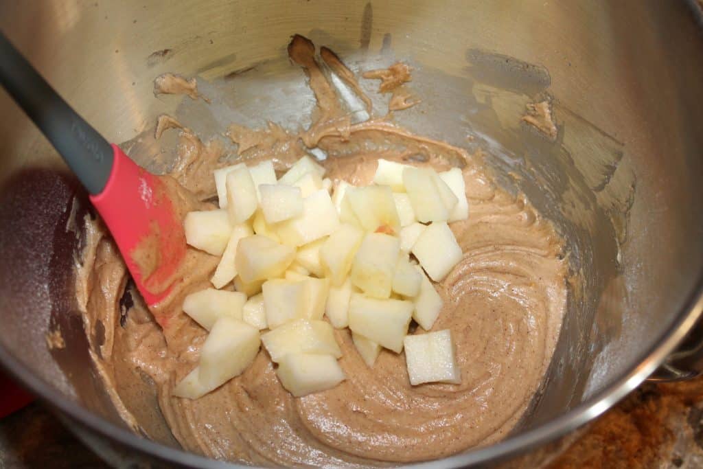 stirring apple chunks into batter with rubber spatula