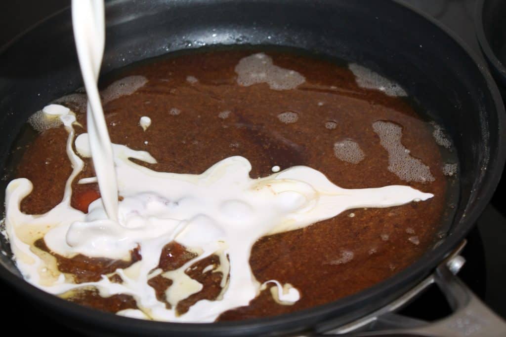pouring heavy whipping cream into the hot caramel in the frying pan