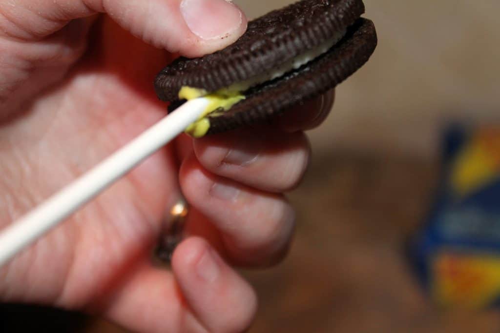 dip your lollipop stick in candy melt and then place it in the oreo