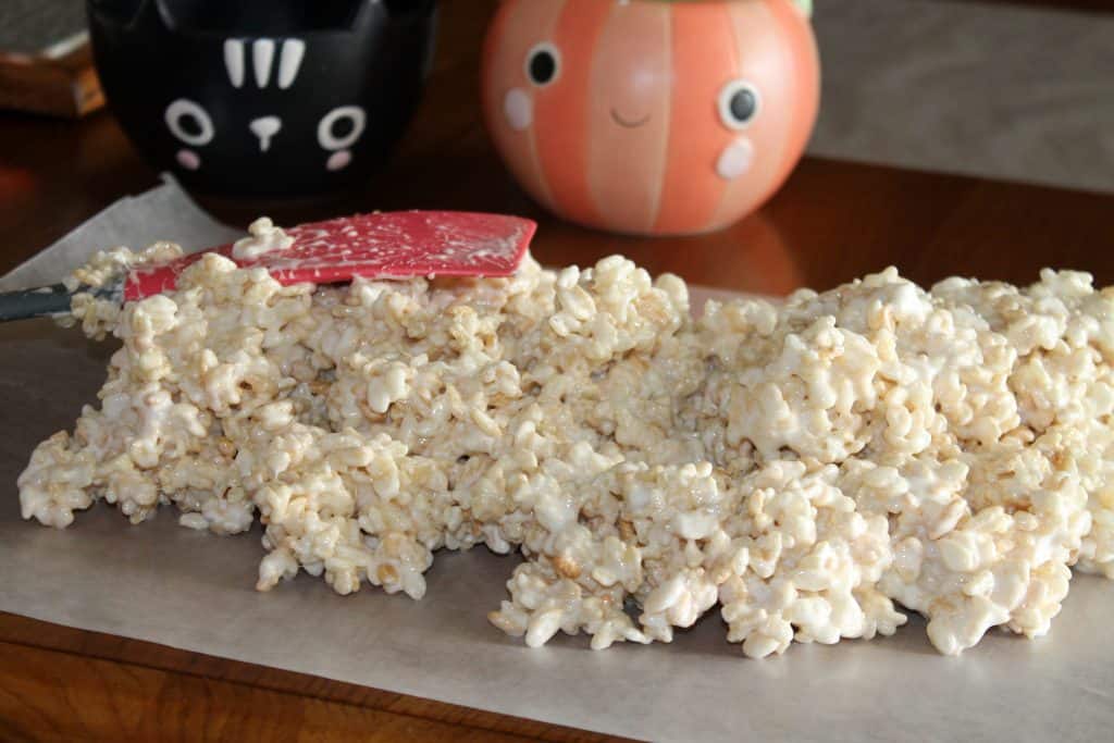 scooping the rice krispie treat mix onto wax paper to cool and harden