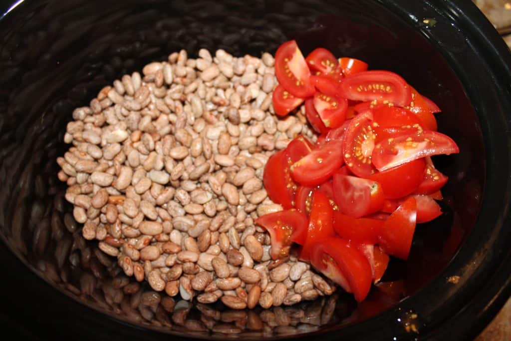adding pinto beans to slow cooker and sliced tomatoes too