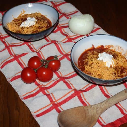 bowls of chili with cheese and sour cream ready to eat