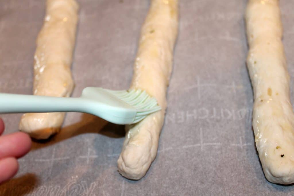 brushing formed breadsticks with butter topping