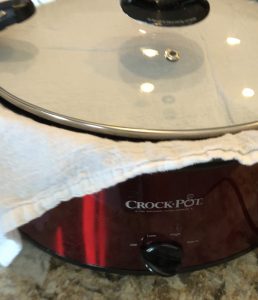 crockpot with a kitchen towel layered between the lid