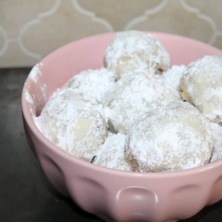 a pink bowl filled with homemade mexican wedding cookies