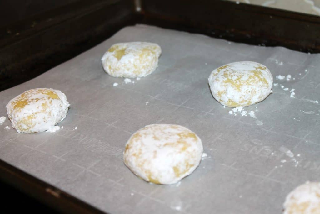 lemon cookie balls on a cookie sheet with parchment paper