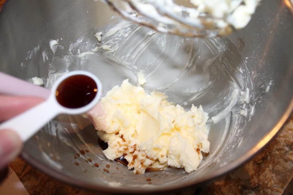 mixing bowl with creamed butter and a teaspoon with vanilla extract