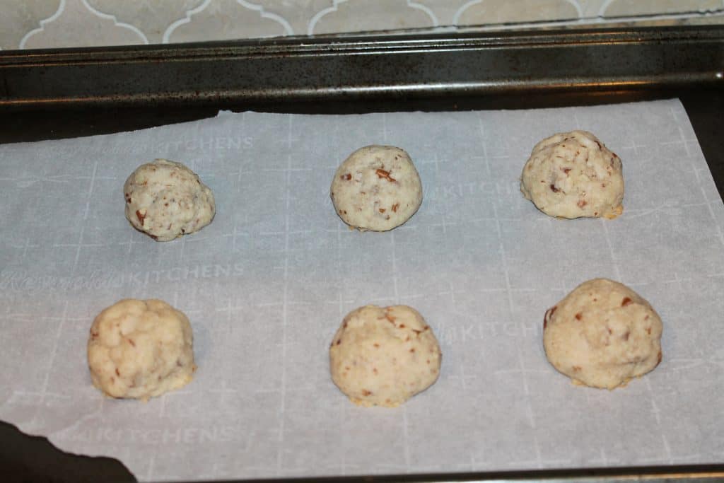 cookie balls placed on cookie sheet lined with parchment paper