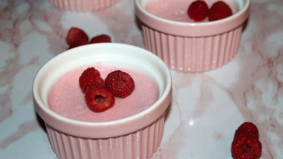 homemade raspberry mouse in a pink ramekin topped with fresh raspberries