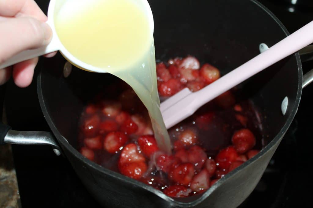 pouring lemon juice into strawberries