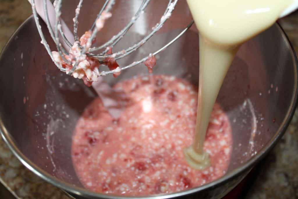 pouring sweetened condensed milk into strawberry lemon cream mixture