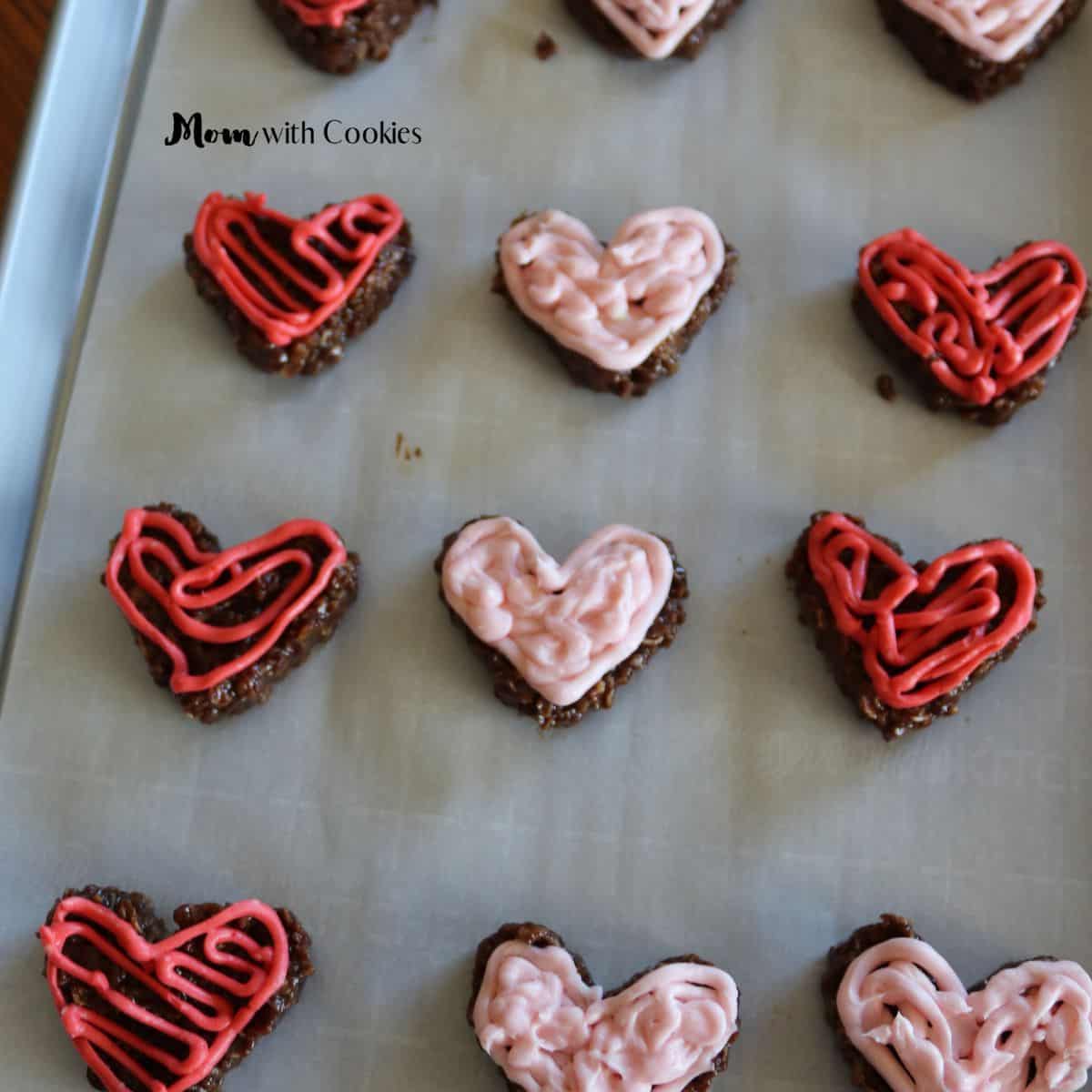a bunch of heart shaped no bake cookies with pink and red cream cheese icing