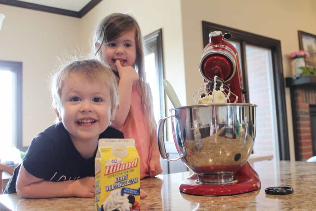 two kids having fun making homemade frosting with mom