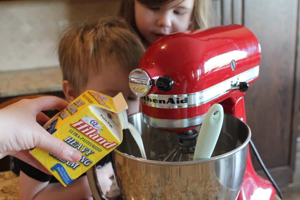 pouring Hiland heavy whipping cream into the mixing bowl