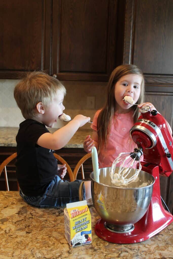 kids eating some whipped cream frosting from spoons