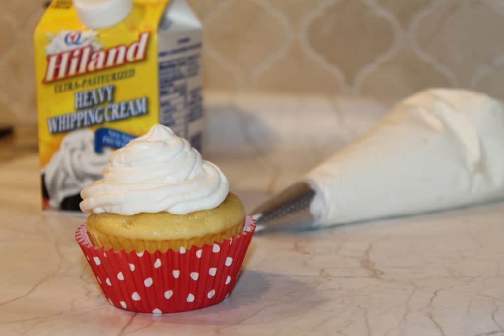 a cupcake with whipped cream frosting and Hiland heavy whipping cream in the background