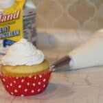 a cupcake with whipped cream frosting and Hiland heavy whipping cream in the background