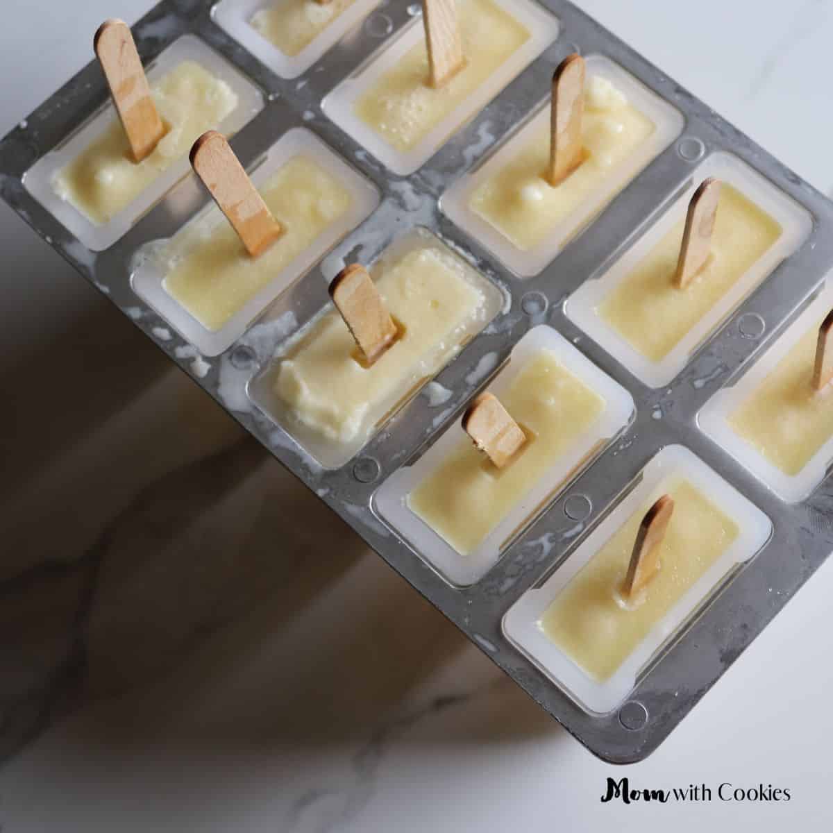 a popsicle mold with orange pineapple creamsicle mixture