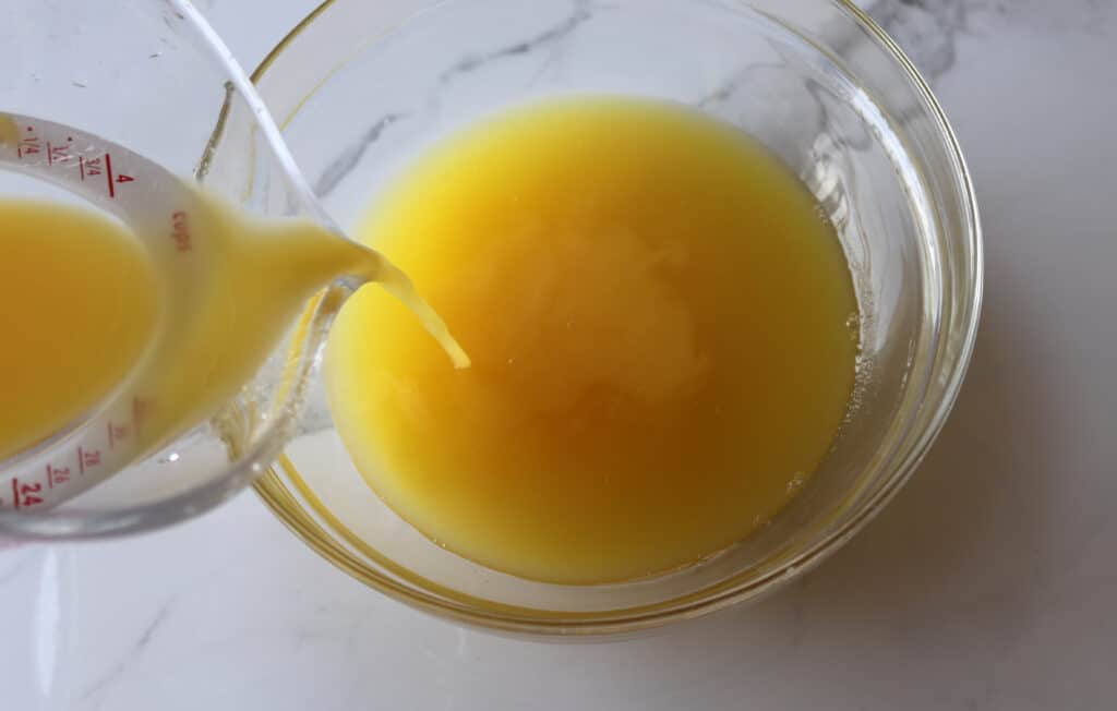 pouring orange juice into the glass bowl with pineapple juice and sugar