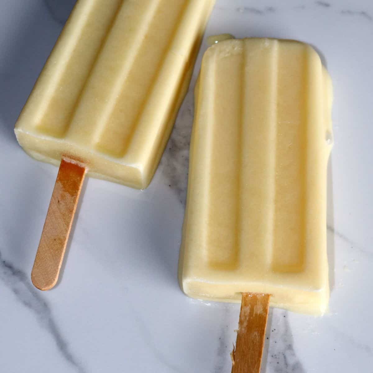 2 orange pineapple creamsicles on a marble slab