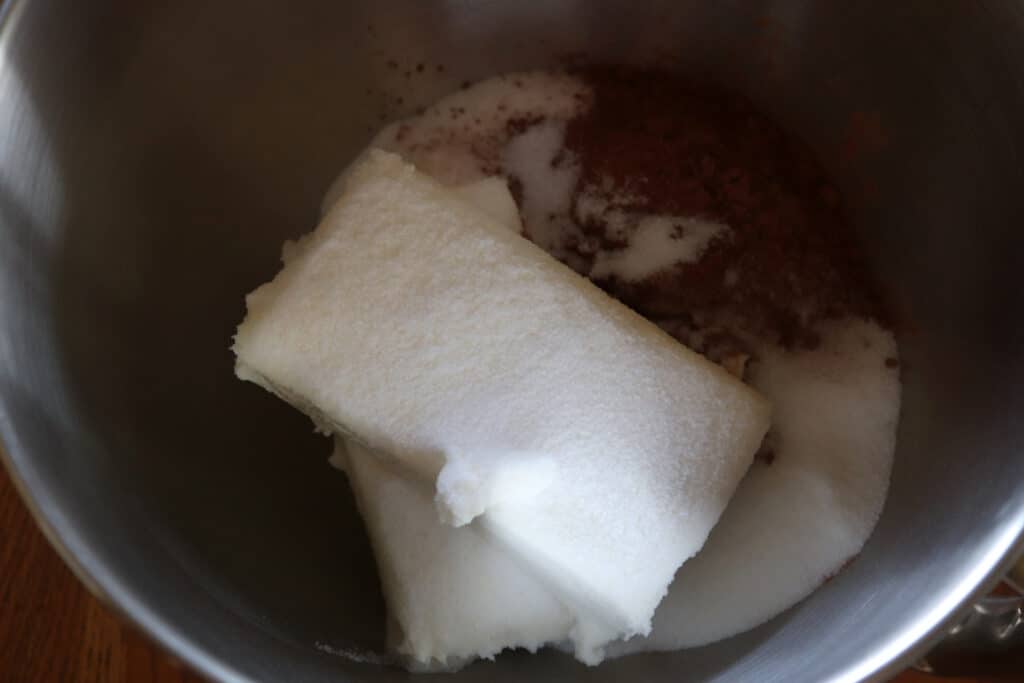 a mixing bowl with cream cheese, sugar and cocoa powder