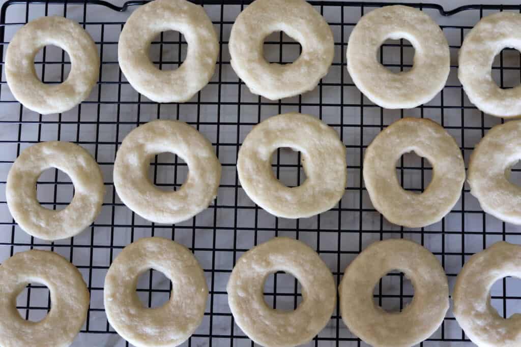 a bunch of baked shortbread cookie rings cooling on a wire rack