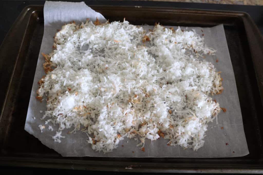 a cookie sheet lined with parchment paper and the toasted shredded coconut
