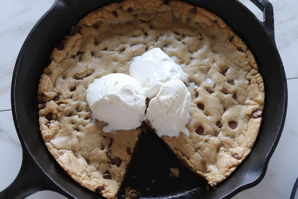 chocolate chip skillet cookie with ice cream on top and a slice missing