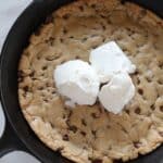 chocolate chip cookie in a cast iron skillet with three scoops of ice cream on top