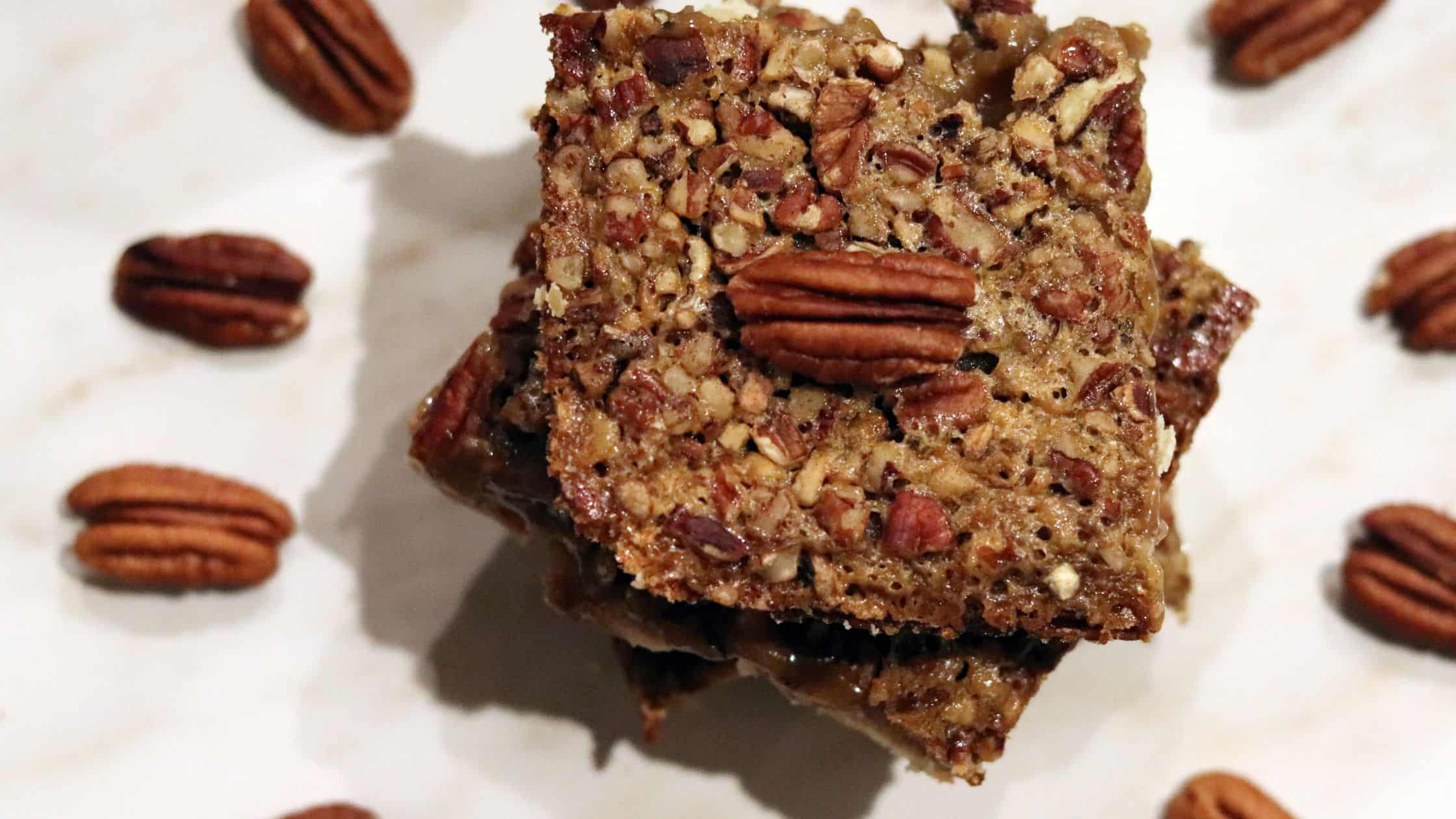 pecan pie bars placed in a decorative way with pecans all around