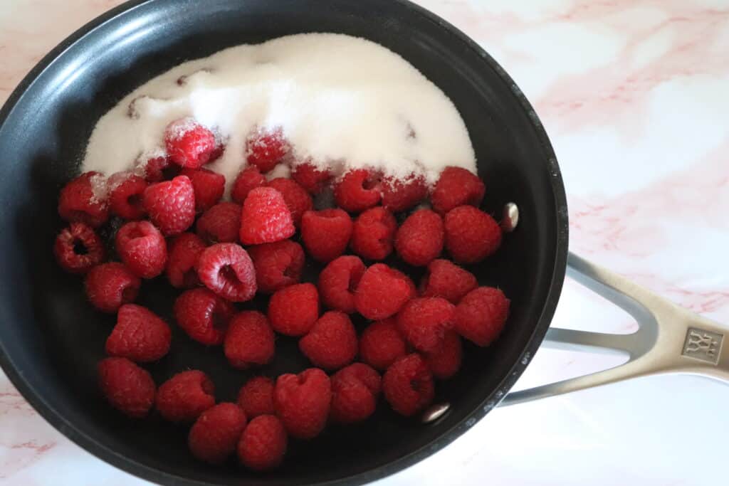 a small frying pan with fresh raspberries and sugar