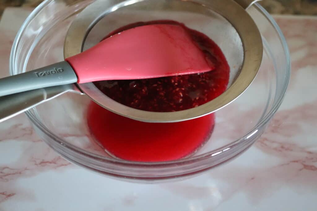 raspberry sauce pressed through a fine mesh strainer to separate seeds