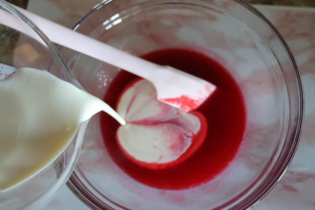 pouring heavy whipping cream into the raspberry sauce