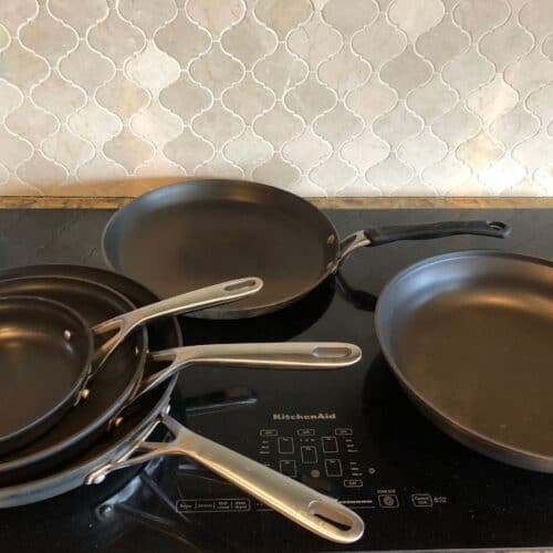 a bunch of different frying pans stacked on a cook top in a kitchen