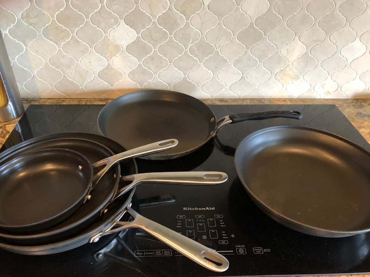 a bunch of different frying pans stacked on a cook top in a kitchen