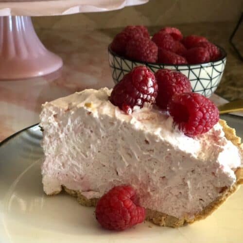 a slice of no bake raspberry cream pie with fresh raspberries on top