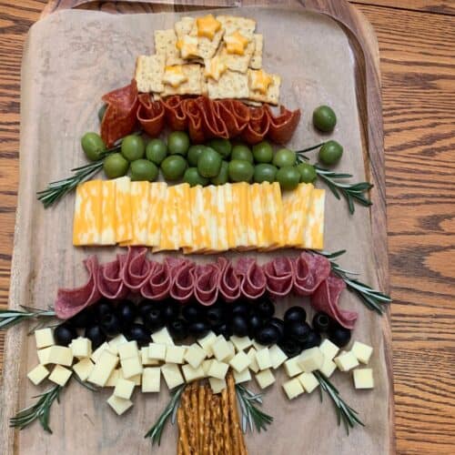 a charcuterie board with meats cheeses olives and crackers shaped like a christmas tree